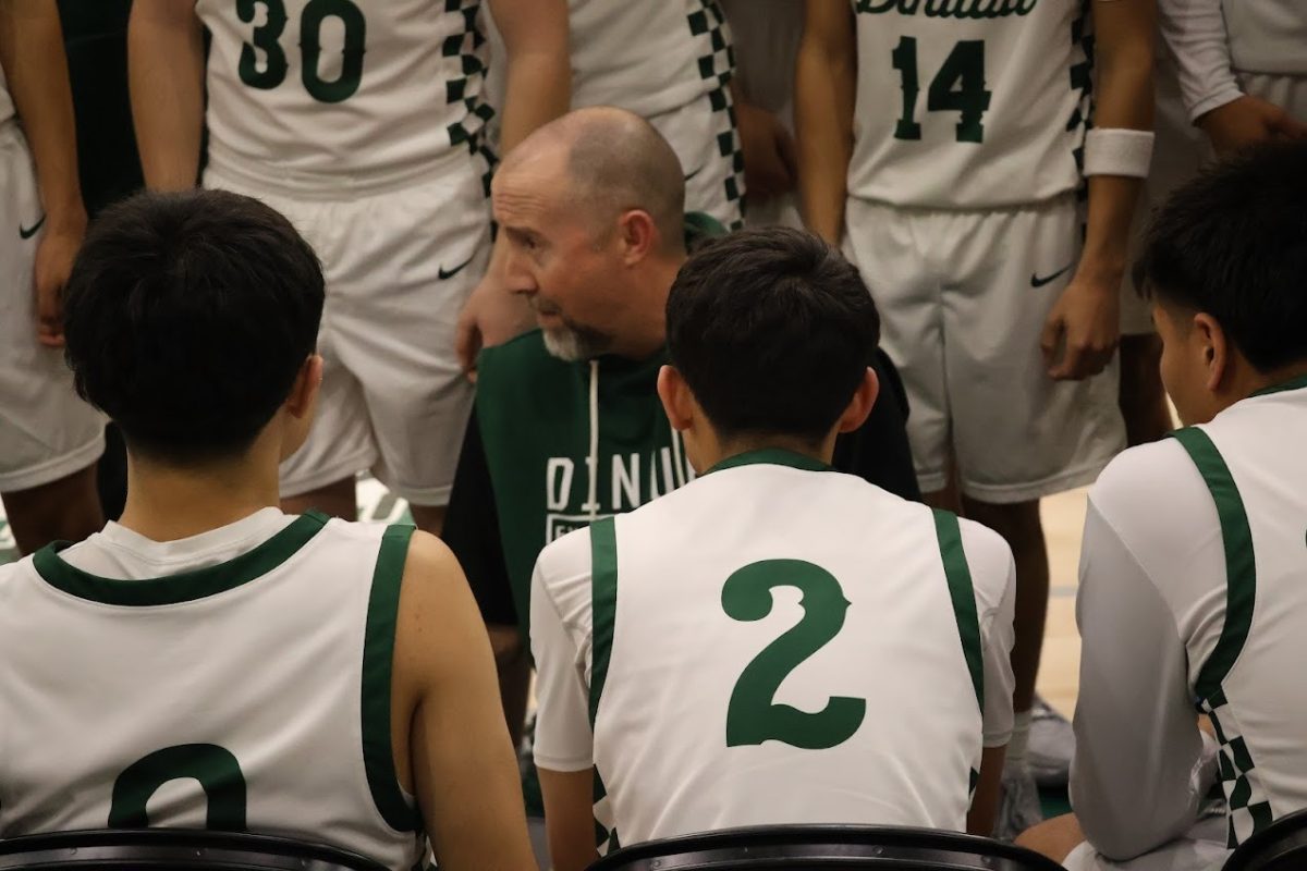 Coach Schofield talking to the team during a time out. Jayden Herrera (2) and Micheal Espirito (0) are sitting in front of him.